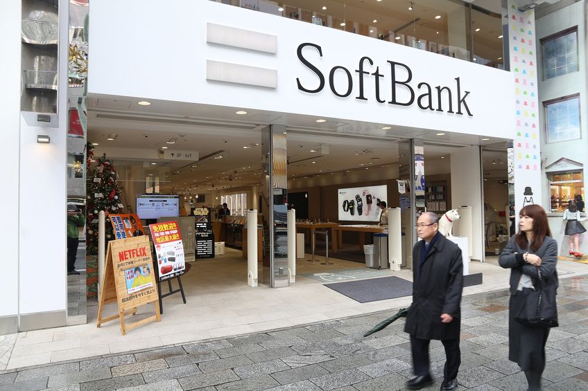 SoftBank retail store entrance in Japan with the company’s logo above the storefront as pedestrians walk past.