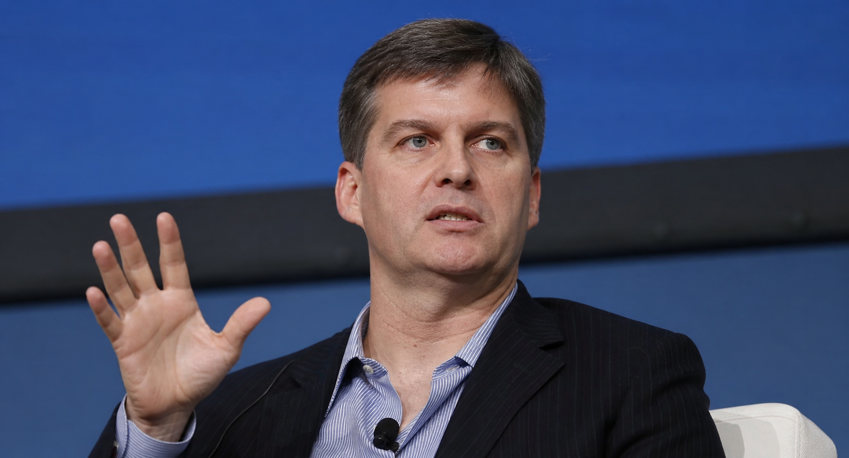 Michael Burry speaks during a financial conference discussion, gesturing while seated on stage.