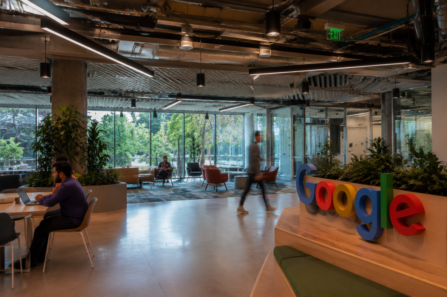 Google logo inside a modern office workspace with employees and lounge areas