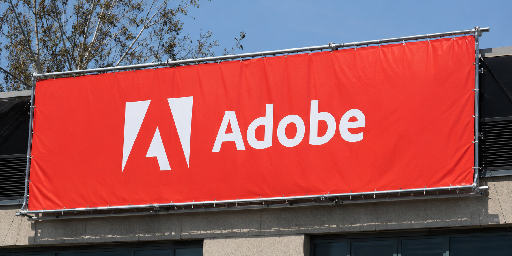 Large red Adobe banner with the company’s white logo and name displayed on the exterior of a building.