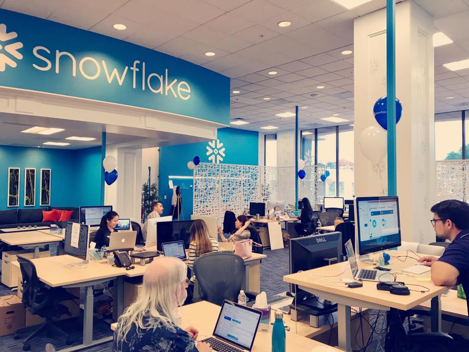 Snowflake employees work inside a bright open-plan office with company branding