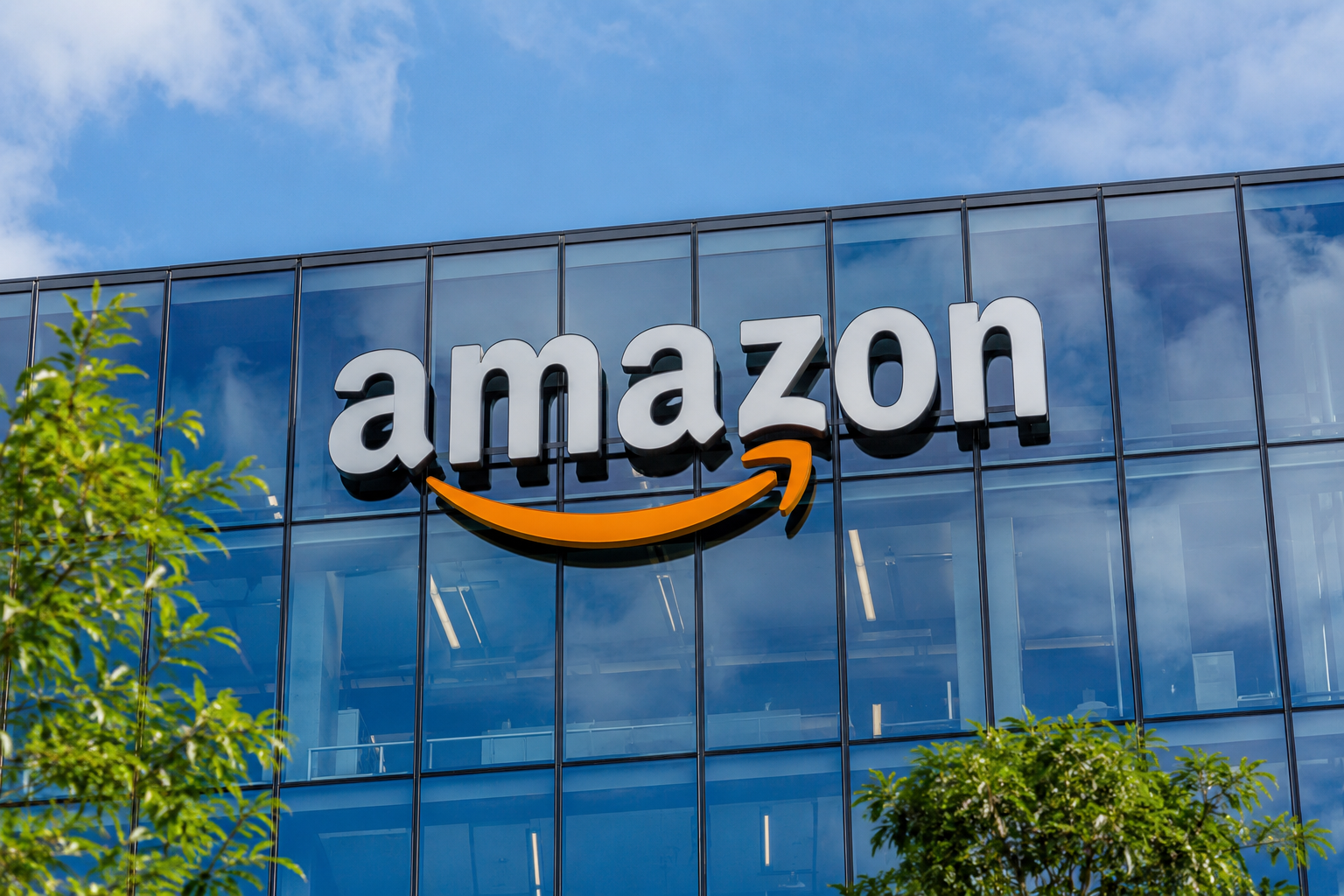 Amazon logo mounted on the glass exterior of a modern corporate office building.